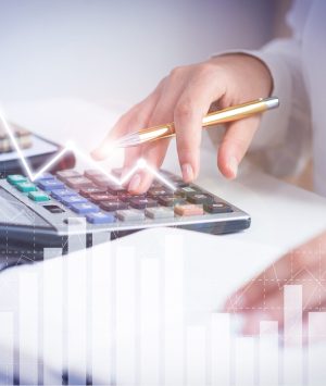 Accountant calculating profit with financial analysis graphs. Notebook, glasses and calculator lying on desk. Accountancy concept. Cropped view.